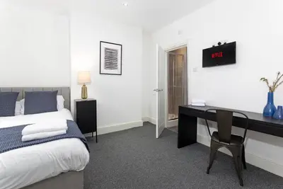 a bedroom with a bed and a desk with a clock on the wall at Host Liverpool - The Wavertree Rooms in Liverpool
