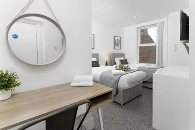 a room with two beds and a mirror on the wall at Host Liverpool - The Wavertree Rooms in Liverpool