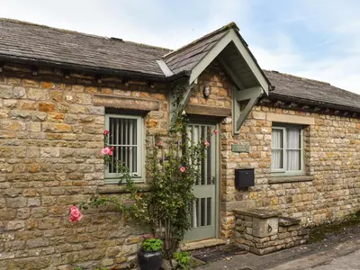 a stone house with roses on the side of it at Mount Cottage in Wennington