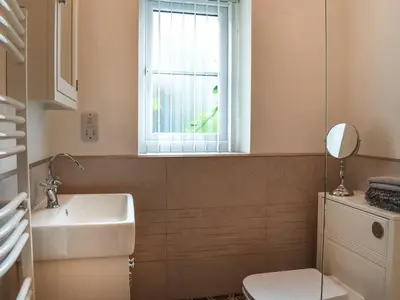 a bathroom with a sink and a toilet and a window at Mount Cottage in Wennington