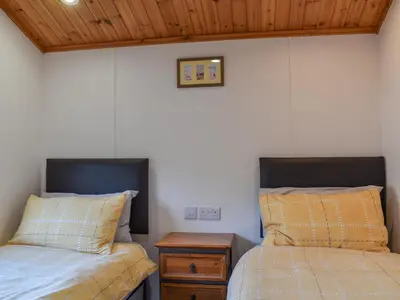 a bedroom with two beds and a wooden ceiling at Serenity in Millom