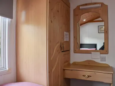 a bathroom with a wooden cabinet and a mirror at Serenity in Millom
