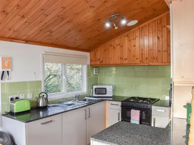 a kitchen with white cabinets and green tiles at Serenity in Millom