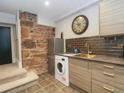 a kitchen with a washing machine and a clock on the wall at Lord William in Preston
