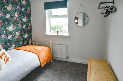 a bedroom with a bed and a mirror and a window at Huntsfield House- Stunning Modern 4 Bedroom House Suitable for Work and Leisure Stays in Bamber Bridge