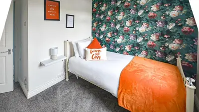 a small bedroom with an orange pillow on a bed at Huntsfield House- Stunning Modern 4 Bedroom House Suitable for Work and Leisure Stays in Bamber Bridge