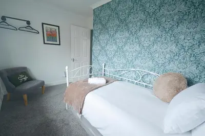 a bedroom with a bed and a chair at Huntsfield House- Stunning Modern 4 Bedroom House Suitable for Work and Leisure Stays in Bamber Bridge