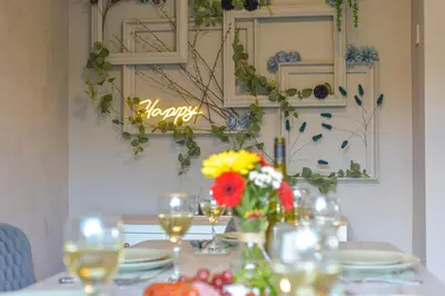 a table with flowers and glasses and a sign that says happy at Huntsfield House- Stunning Modern 4 Bedroom House Suitable for Work and Leisure Stays in Bamber Bridge
