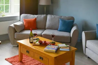 a living room with a couch and a table with wine glasses at Huntsfield House- Stunning Modern 4 Bedroom House Suitable for Work and Leisure Stays in Bamber Bridge