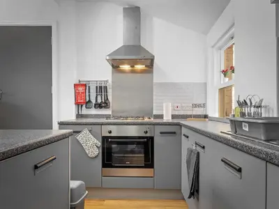 a kitchen with a stove top oven next to a sink at Preston Serviced Apartment - Estatevision in Preston
