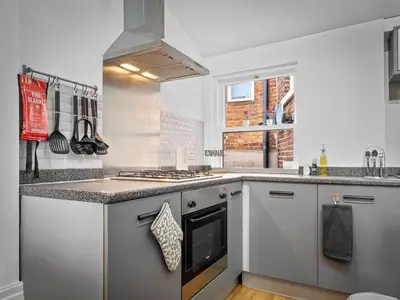 a kitchen with white cabinets and a stove top oven at Preston Serviced Apartment - Estatevision in Preston