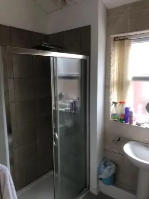 a shower with a glass door in a bathroom at Room in town centre in Saint Helens