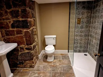 a bathroom with a toilet and a stone wall at Hamilton - Lord William in Scorton