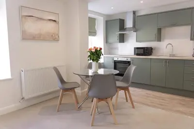 a kitchen with a table with chairs and a vase of flowers at Lonsdale House Boutique Apartments in Ulverston
