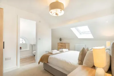 a white bedroom with a bed and a skylight at Lonsdale House Boutique Apartments in Ulverston
