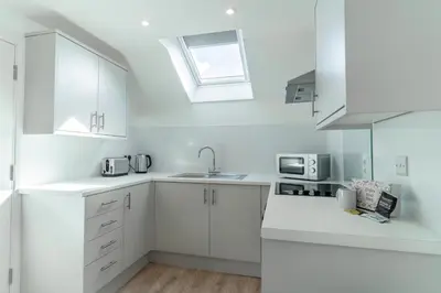 a white kitchen with white cabinets and a sink at Lonsdale House Boutique Apartments in Ulverston
