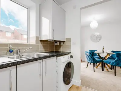 a white kitchen with a washing machine and a table at Modern and Cozy Kirkby Retreat Parking Sleeps 5 - Pass the Keys in Knowsley