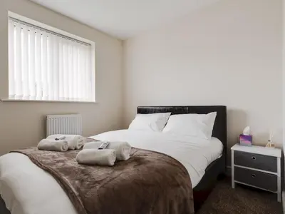 a bedroom with a large bed with towels on it at Modern and Cozy Kirkby Retreat Parking Sleeps 5 - Pass the Keys in Knowsley