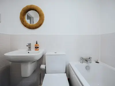 a bathroom with a toilet and a sink and a mirror at Modern and Cozy Kirkby Retreat Parking Sleeps 5 - Pass the Keys in Knowsley