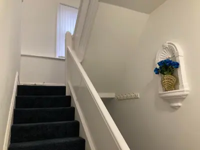 a staircase with a vase with blue flowers on the wall at AGAPI APARTMENT - SEA VIEW SLEEPS TEN in Blackpool