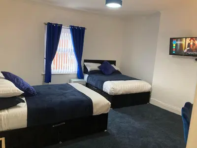 a hotel room with two beds and a television at AGAPI APARTMENT - SEA VIEW SLEEPS TEN in Blackpool