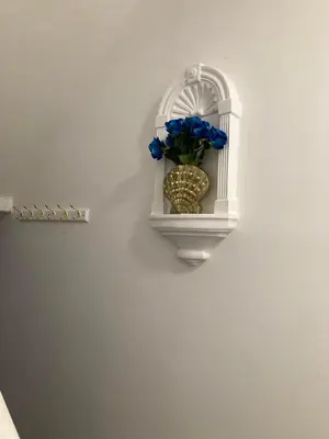 a white wall with a vase with blue flowers in it at AGAPI APARTMENT - SEA VIEW SLEEPS TEN in Blackpool