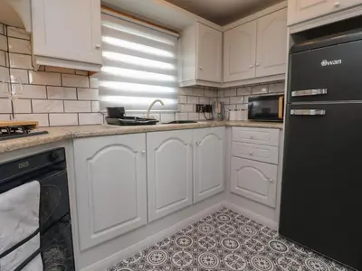 a kitchen with white cabinets and a black refrigerator at Old Bell Farm in Preston