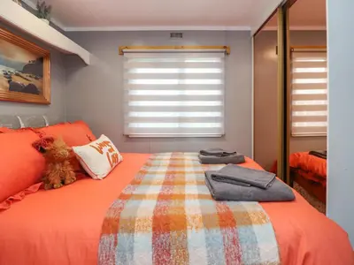 a bedroom with a bed with orange sheets and a window at Old Bell Farm in Preston