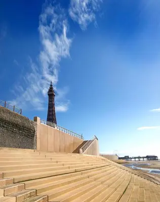 a lighthouse on the beach with a wall and stairs at Cliffs Hotel in Blackpool