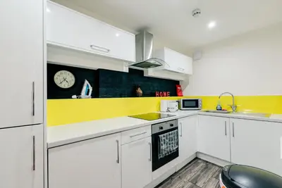 a kitchen with white cabinets and a clock on the wall at Duke Street Apartment Hotel Liverpool City Centre in Liverpool