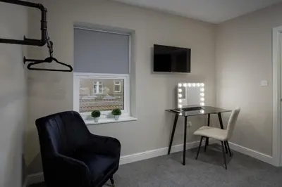 a room with a chair and a table and a window at The Blackpool Beach Boutique Apartments in Blackpool