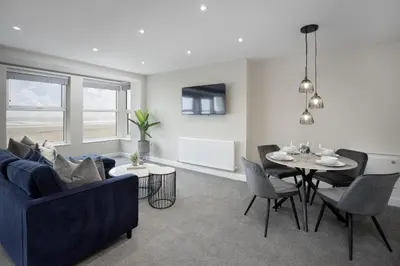 a living room with a blue couch and a table at The Blackpool Beach Boutique Apartments in Blackpool