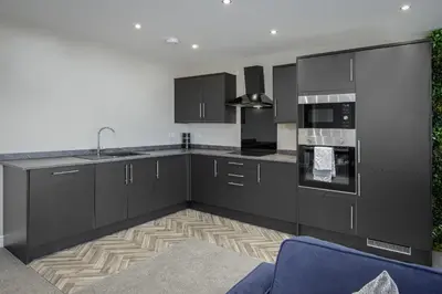a kitchen with black cabinets and a blue chair at The Blackpool Beach Boutique Apartments in Blackpool