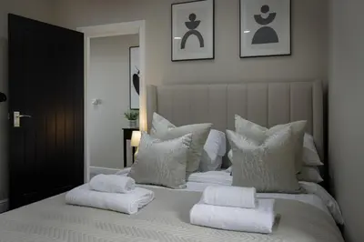 a white bed with pillows and towels on it at The Blackpool Beach Boutique Apartments in Blackpool