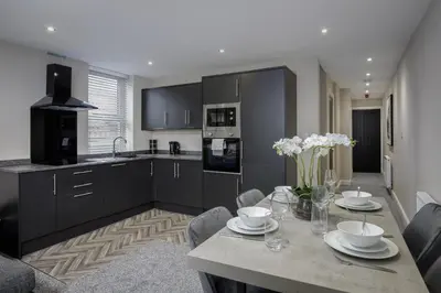 a kitchen with a table with white flowers on it at The Blackpool Beach Boutique Apartments in Blackpool