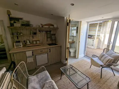 a living room with a table and chairs and a kitchen at La Cachette in Blackpool