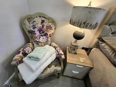 a bedroom with a chair and a table with a lamp at Windmill House LYTHAM in Lytham St Annes