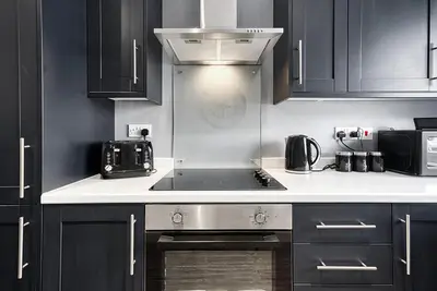 a kitchen with black cabinets and a stove top oven at Stylish 2 Bed Apartment with Free Parking in Preston