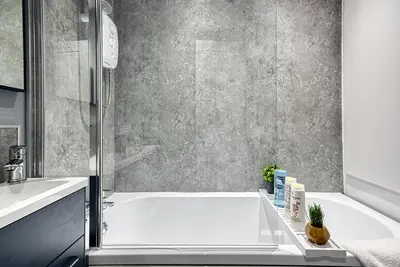 a bathroom with a white tub and a sink at Stylish 2 Bed Apartment with Free Parking in Preston