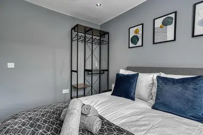 a bedroom with a large bed with blue pillows at Stylish 2 Bed Apartment with Free Parking in Preston