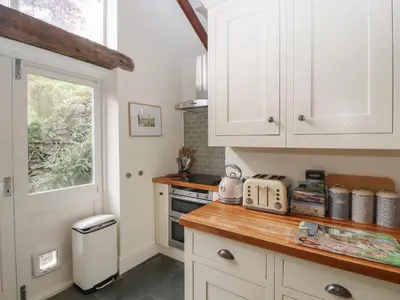 a kitchen with white cabinets and a window at 3 Tower View in Grange Over Sands