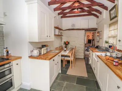 a kitchen with white cabinets and a table in it at 3 Tower View in Grange Over Sands