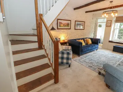 a living room with a staircase and a blue couch at 3 Tower View in Grange Over Sands