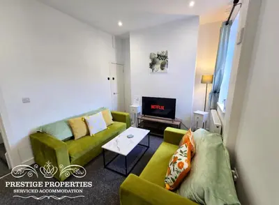 a living room with two green couches and a tv at 16 Newcastle street by Prestige Properties Serviced Accommodation in Barrow in Furness