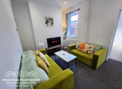 a living room with two green couches and a tv at 16 Newcastle street by Prestige Properties Serviced Accommodation in Barrow in Furness