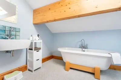 a bathroom with a large white tub and a sink at Large converted barn in peaceful, rural location in Hambleton