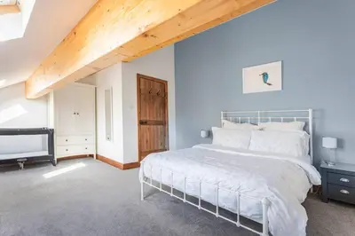 a bedroom with a white bed and a wooden ceiling at Large converted barn in peaceful, rural location in Hambleton