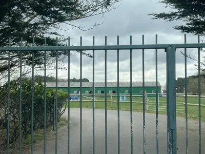 a gate in front of a field with a building at Let It Be in Liverpool
