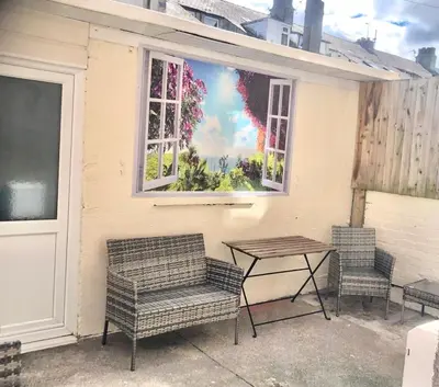 a patio with two chairs and a table and a mural at Eden Stay 5 Bedroom House in Morecambe