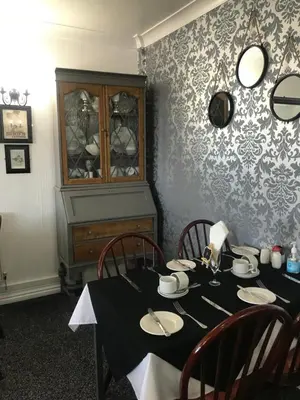 a dining room with a table with chairs and a cabinet at The Rutland in Blackpool